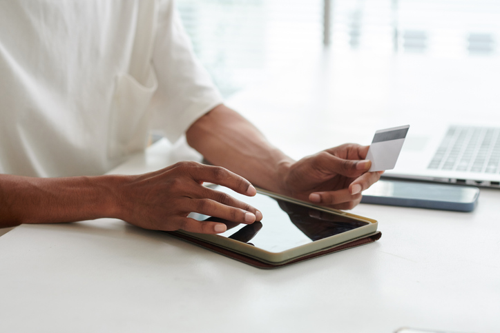 Hands of young African American man with credit card and tablet