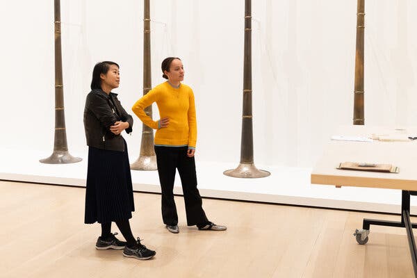 Ms. Kuo, dressed in black and wearing sneakers, and Ms. Wales Bonner, in a sunflower yellow pullover and black slacks, look appraisingly at the museum installation in progress. Behind them is an artwork that resembles very elongated horns. 