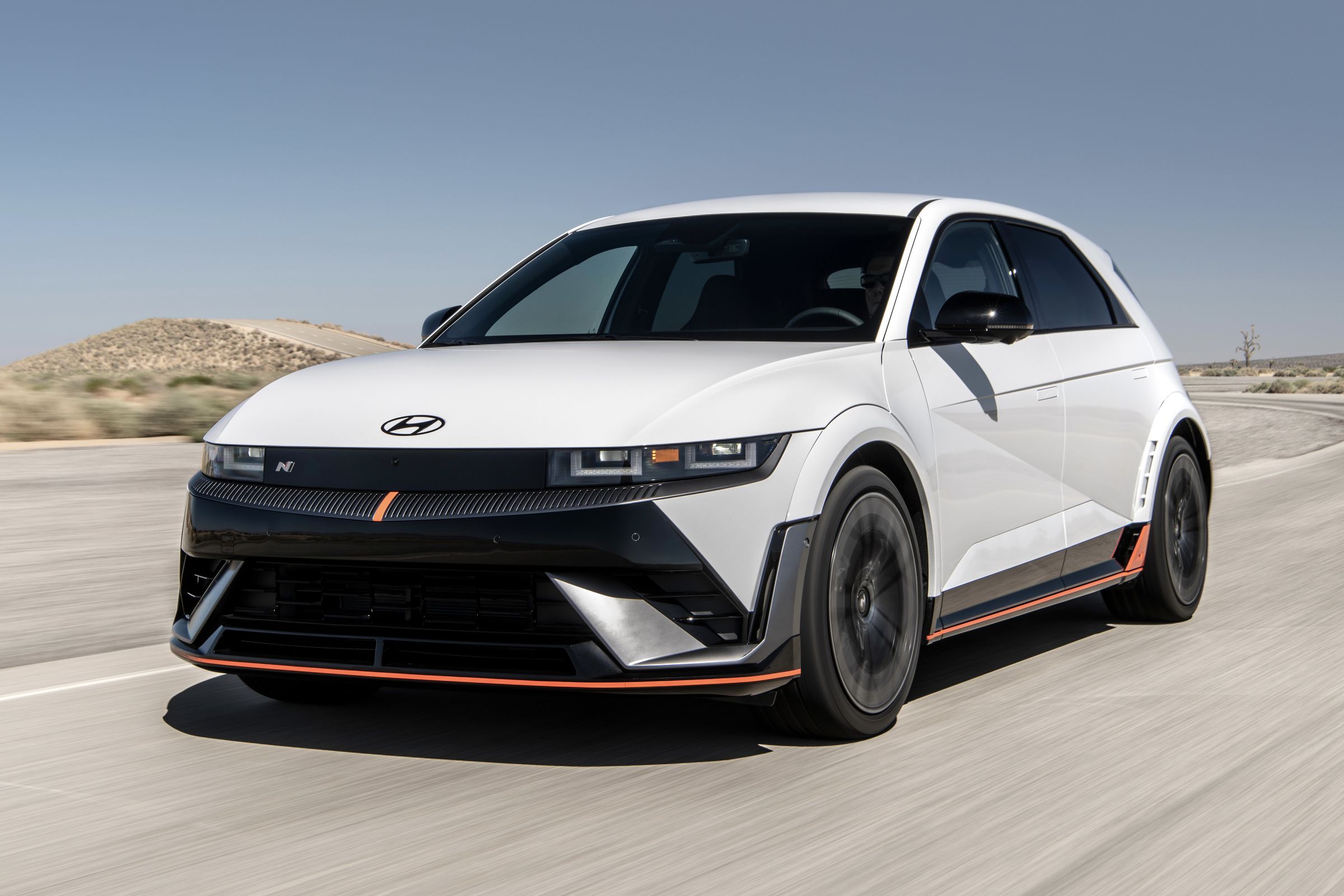 Ioniq 5 N driving, camera ahead looking at front, desert background, car is white with black front and orange pencil skirt