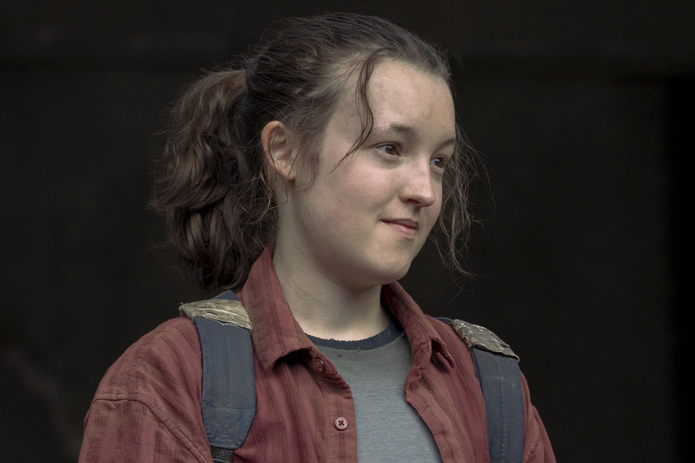 A teenager wearing a gray T-shirt under a red flannel, as well as a backpack.