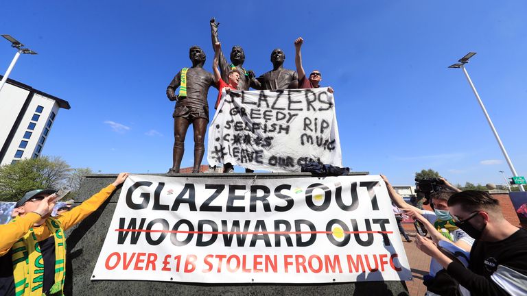 Manchester United fans hung banners and scarves on the Trinity Statue outside Old Trafford