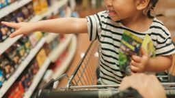 POV angle Asian Toddler female very happy to buying a snack and sitting in shopping cart with her parent