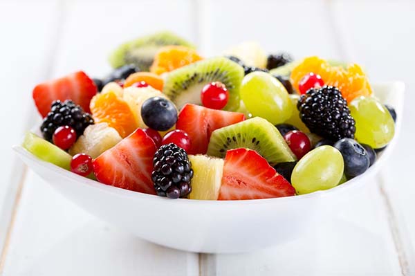 photo of a bowl of fruit containing strawberries, blueberries, cherries, grapes, pineapple, and kiwi