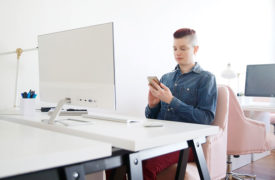 A person sitting at a desk and looking at their phone