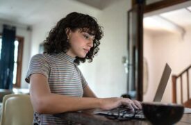 trans woman at home researching on laptop