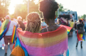 Two people wrapped up in a rainbow flag