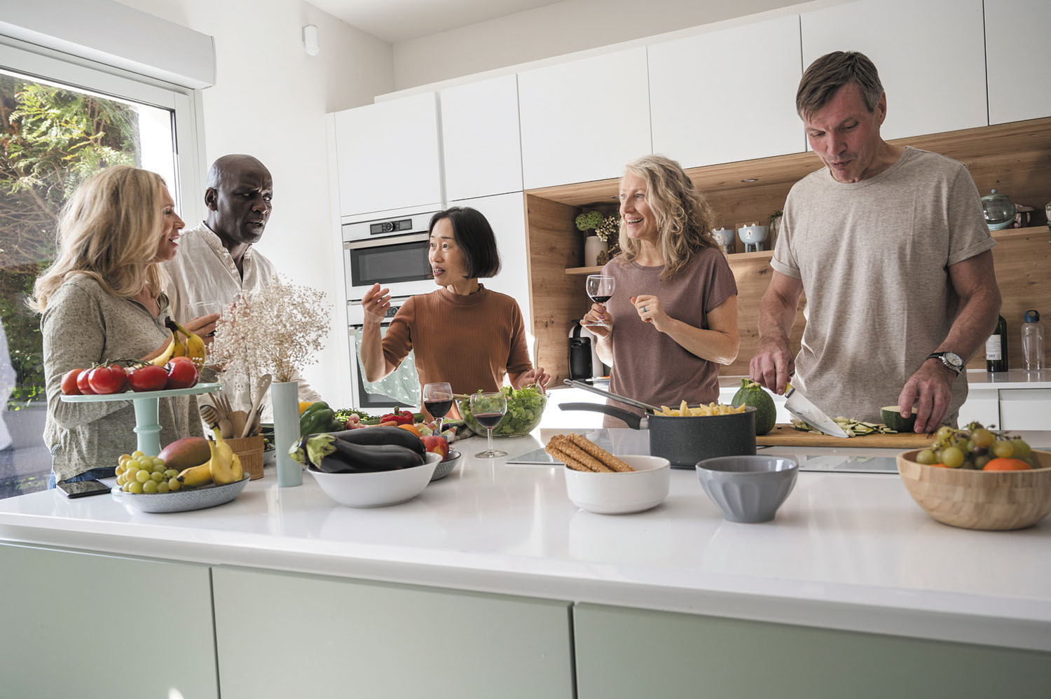 photo of a group of friends gathered in a kitchen preparing healthy food