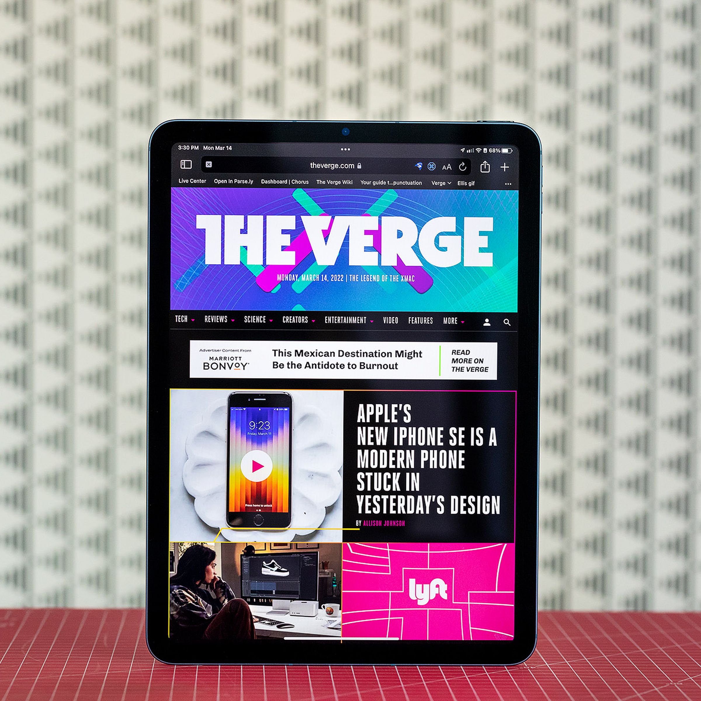 The iPad Air standing on a red table in front of a white background.