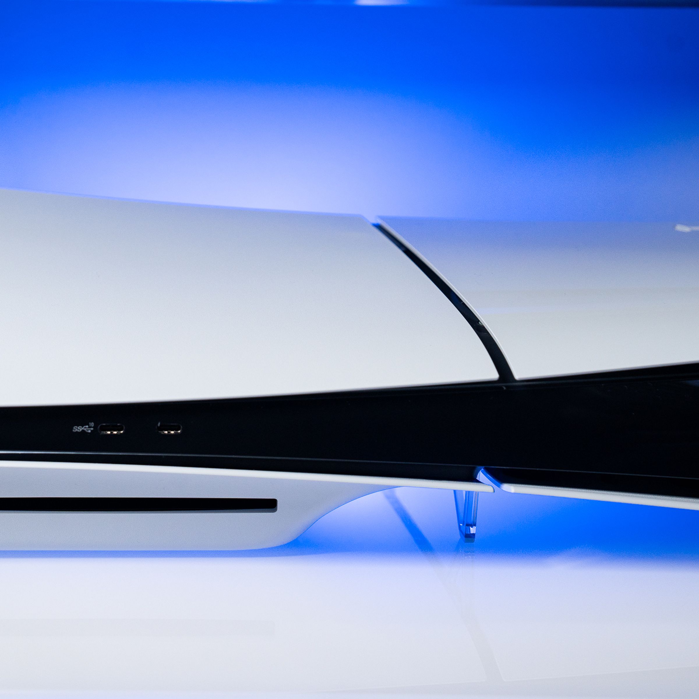 The PlayStation 5 slim sitting on a white surface with a blue backlight.