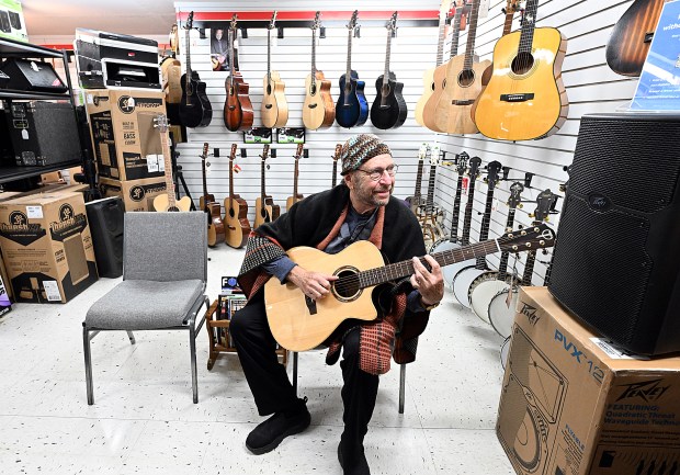 Long-time customer Rick Nelson tells Don Jensen, not pictured, owner of Willow River Music, "I think I found my next dream guitar" while playing the instrument Thursday, Dec. 14, 2023, at the new music shop in downtown Loveland. Jensen had a shop in Longmont before moving it to Loveland. (Jenny Sparks/Loveland Reporter-Herald)