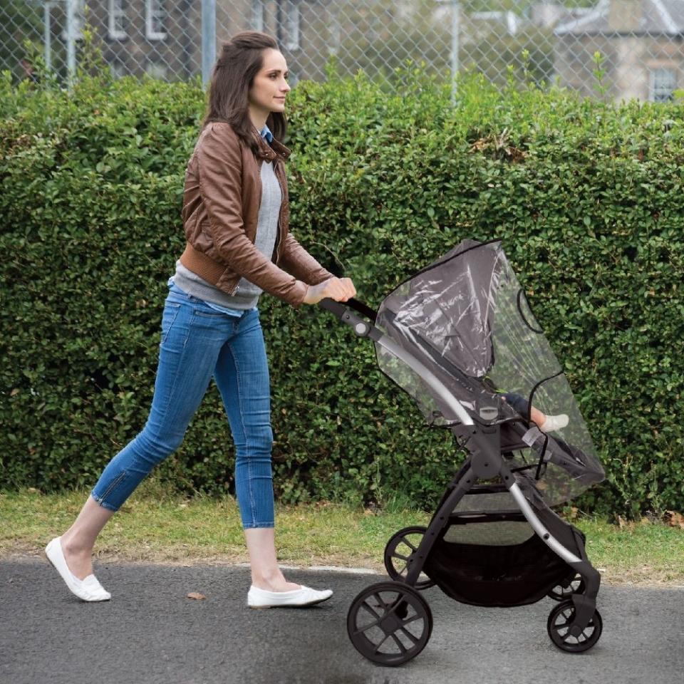 a person pushing a child in a stroller with the shield over it