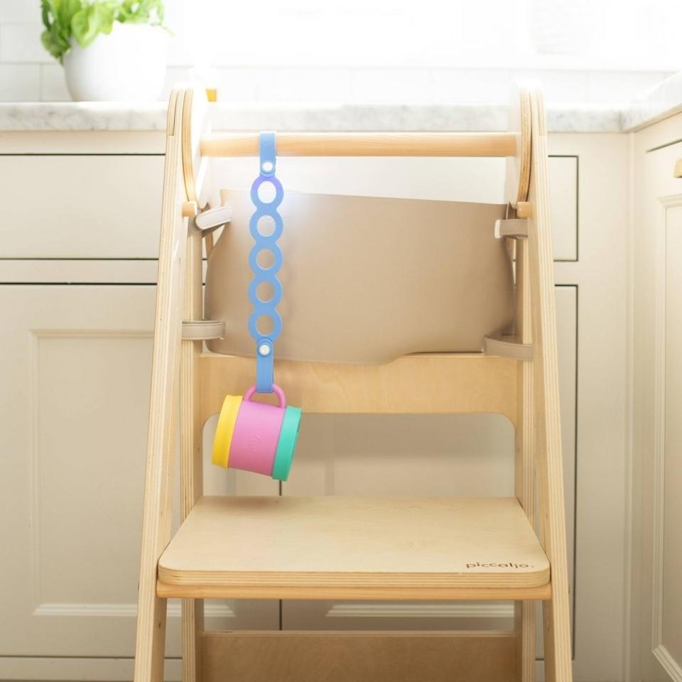 a cup hanging on the strap connected to a chair so it doesn't fall on the floor