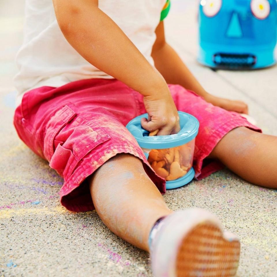 a child reaching for a snack in the container