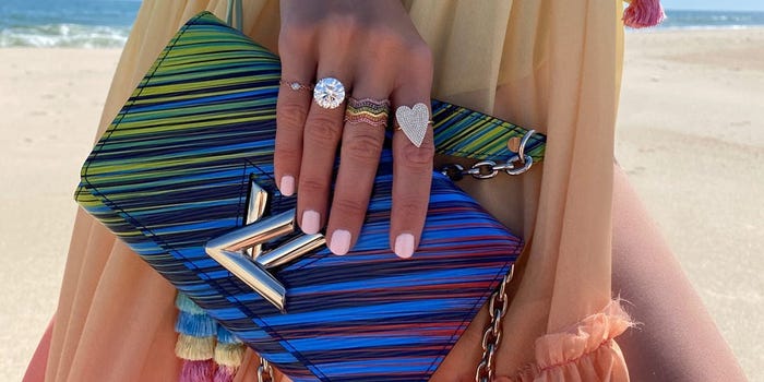 Closeup of a person's hand holding a luxury brand clutch.