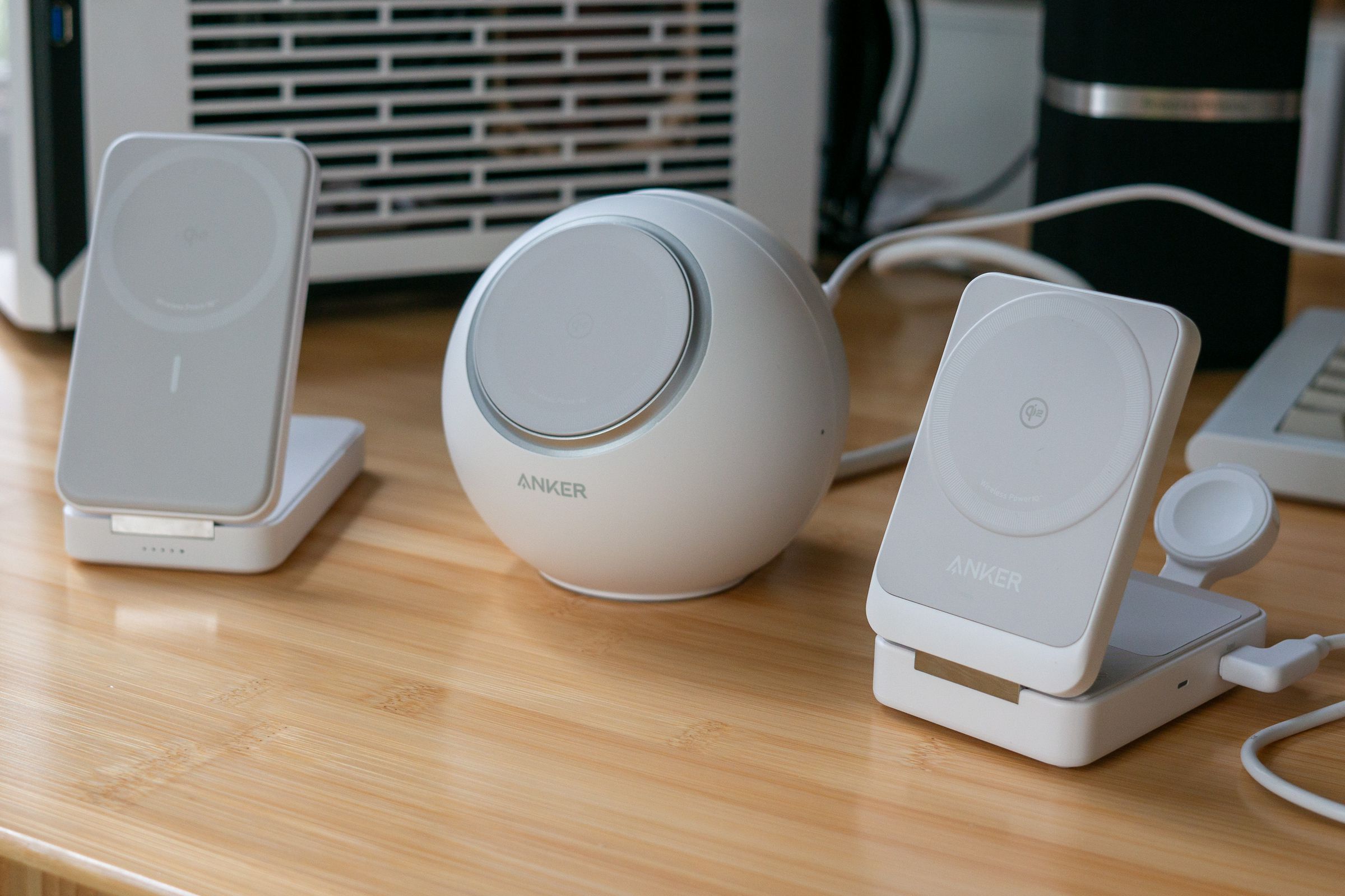 Three grey-and-white Anker chargers on a bamboo desktop. 