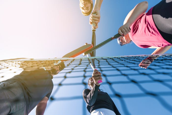 four pickleball players with rackets at net