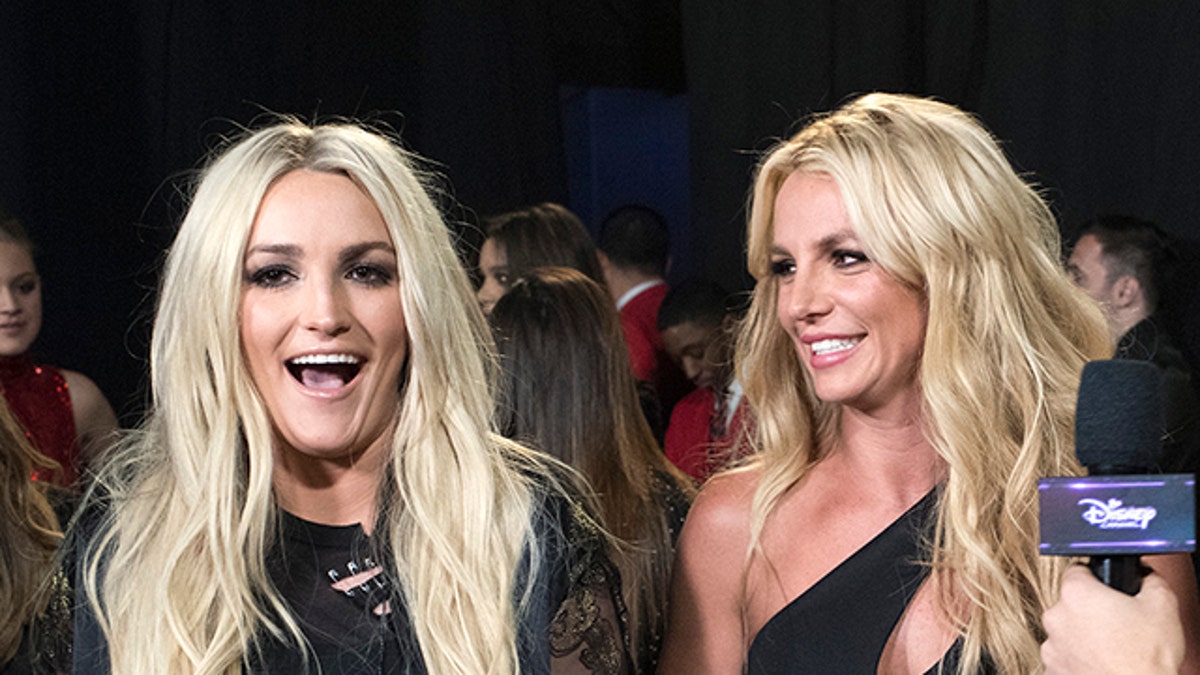 Jamie Lynn Spears laughs as she stands next to sister Britney, both wearing black