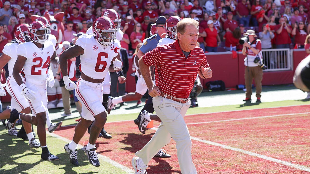 Nick Saban leads his team onto the field against Arkansas