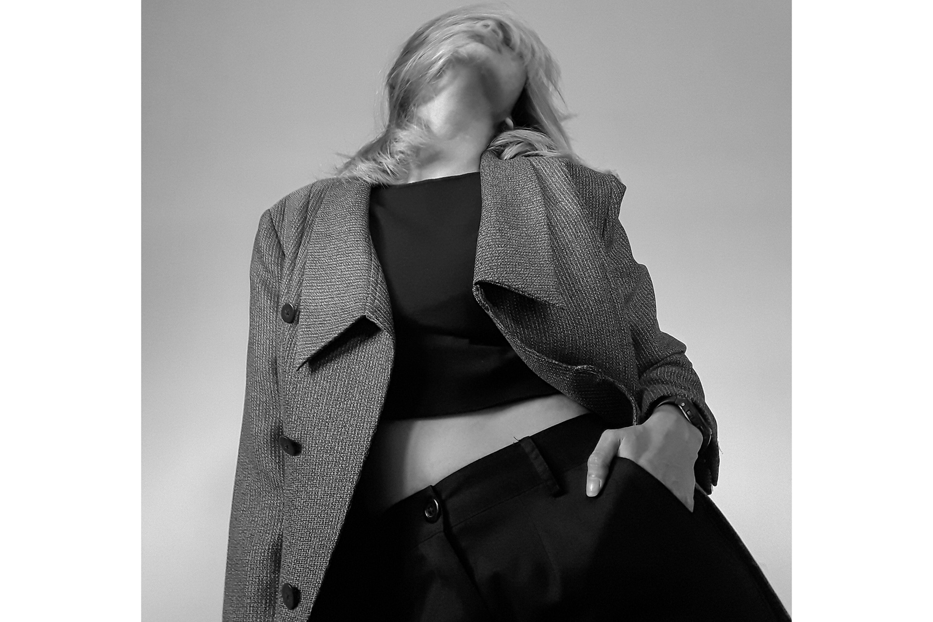 Black and white photo of model in houndstooth blazer with her head thrown back.