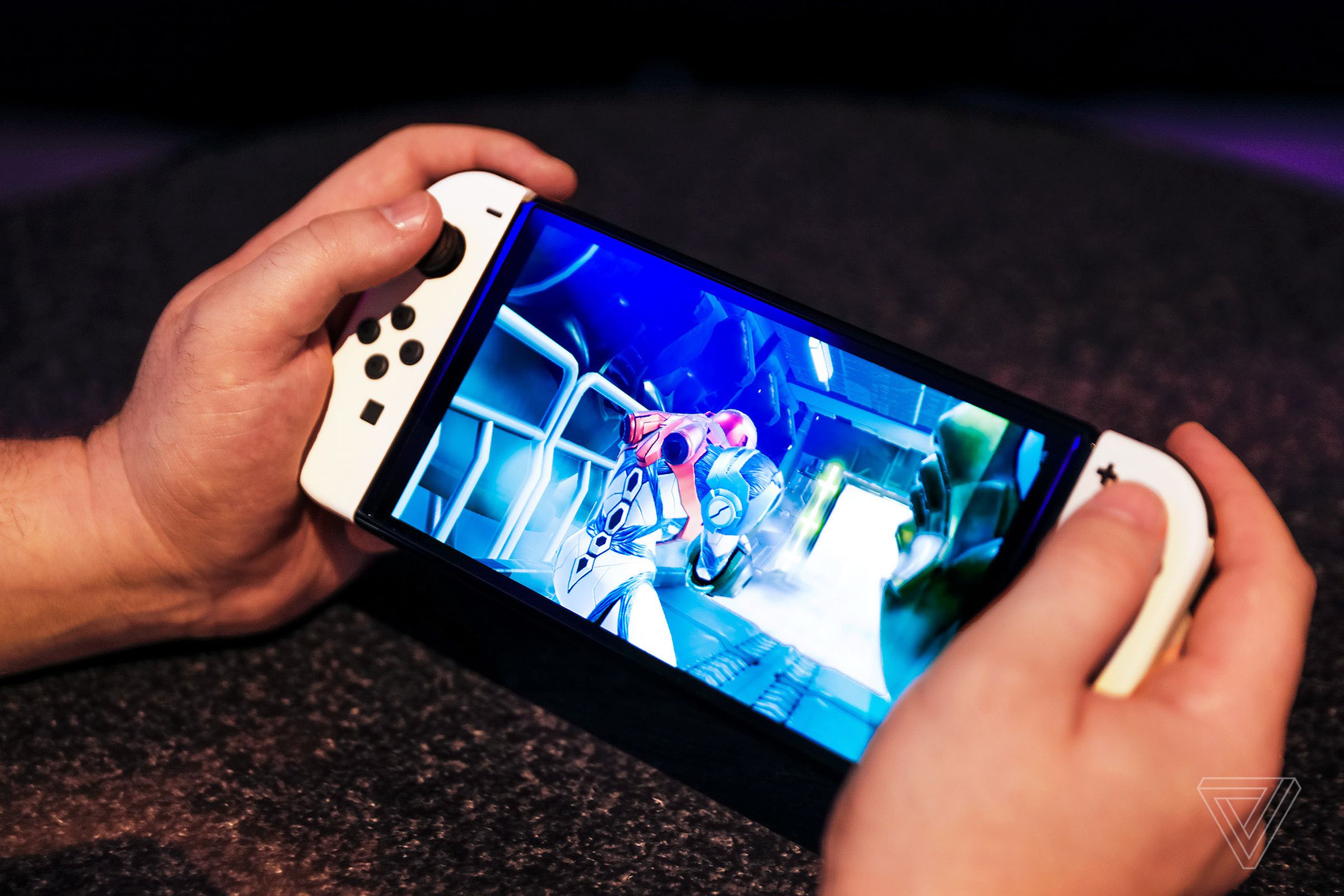 A pair of hands holding the Nintendo Switch OLED