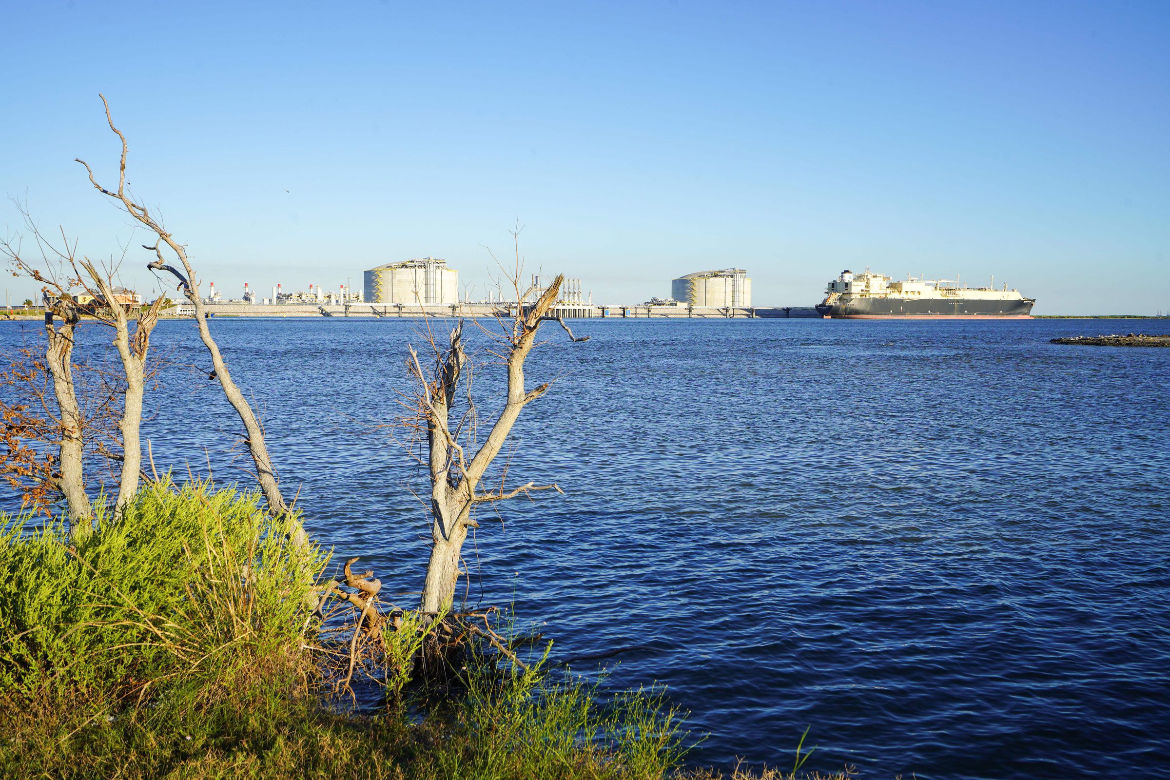 A ship seen next to a gas export terminal on the shoreline.