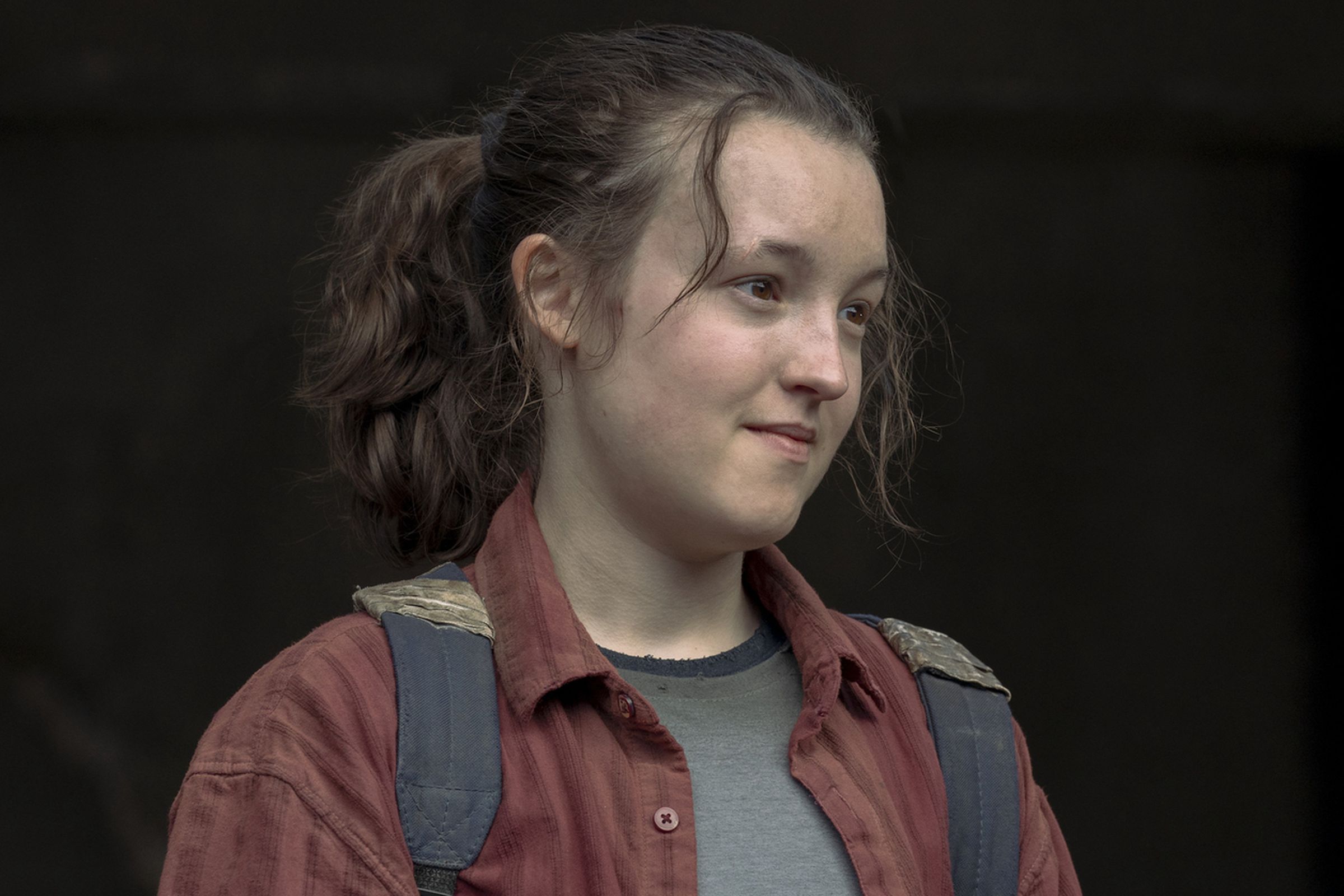 A teenager wearing a gray T-shirt under a red flannel, as well as a backpack.