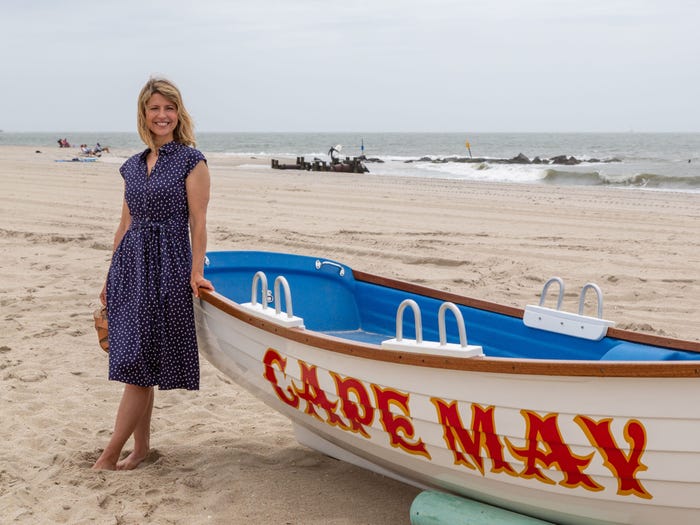 Samantha brown posing with a cape may boat on a beach by the ocean on a hazy day