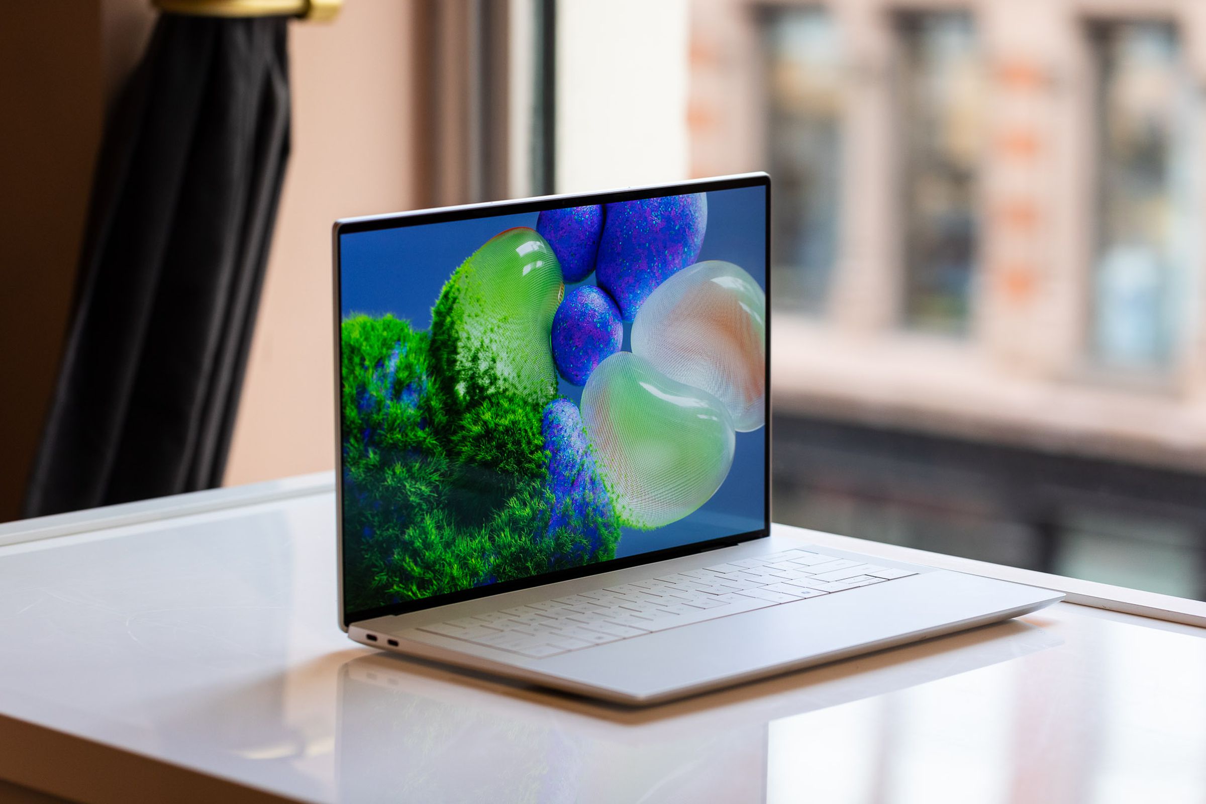 A white laptop with thin bezels sitting on a table.