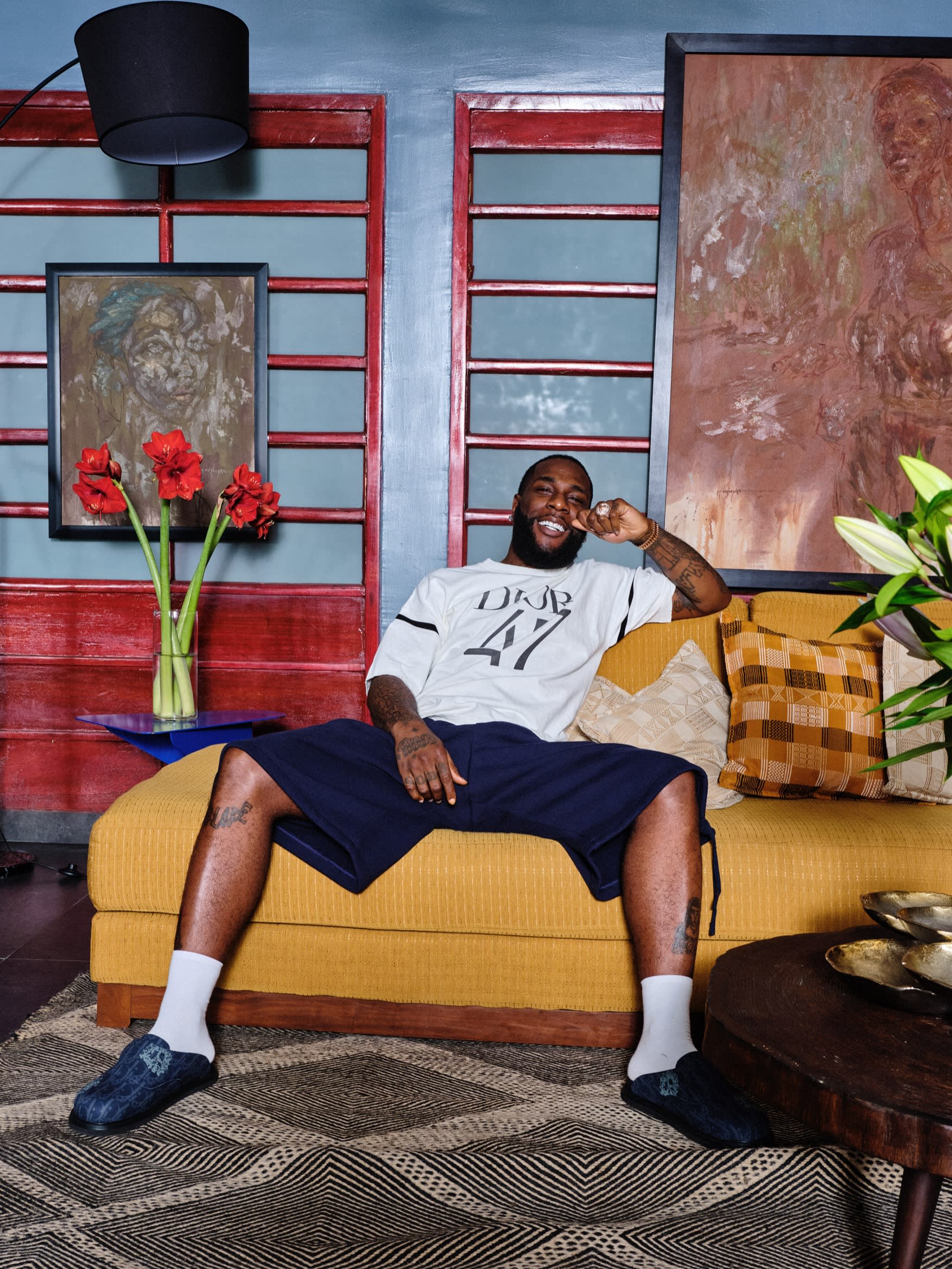 Dior Men cotton oversized T-shirt, £990, and cotton fleece Bermuda shorts, £1,150. Socks and Dior Men denim Tears Aqua mules, Burna Boy’s own. Artworks by Midegbeyan Ojisua