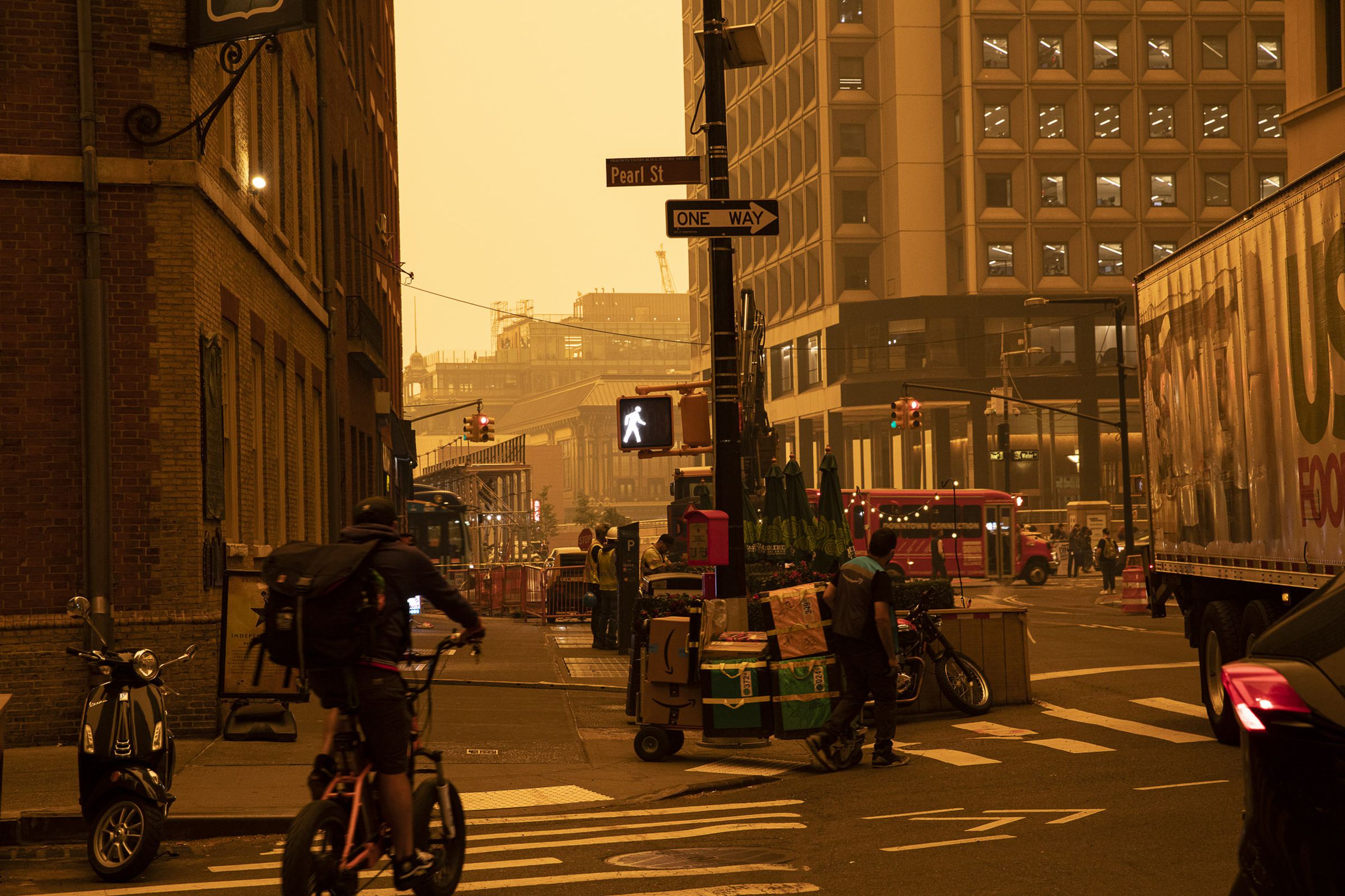 A biker at a street corner against an orange sky hazy with smoke.