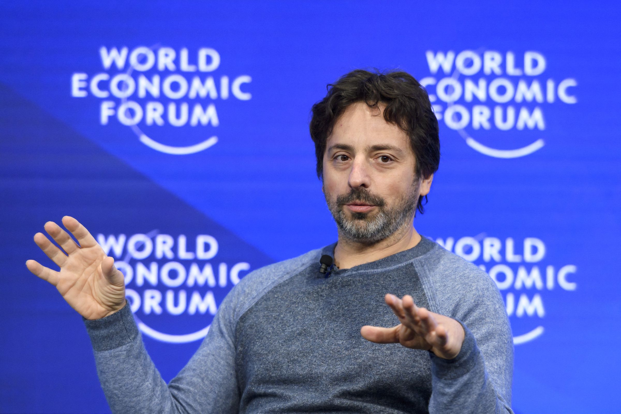 A picture of Sergey Brin holding his hands up mid-gesture while speaking at the World Economic Forum.