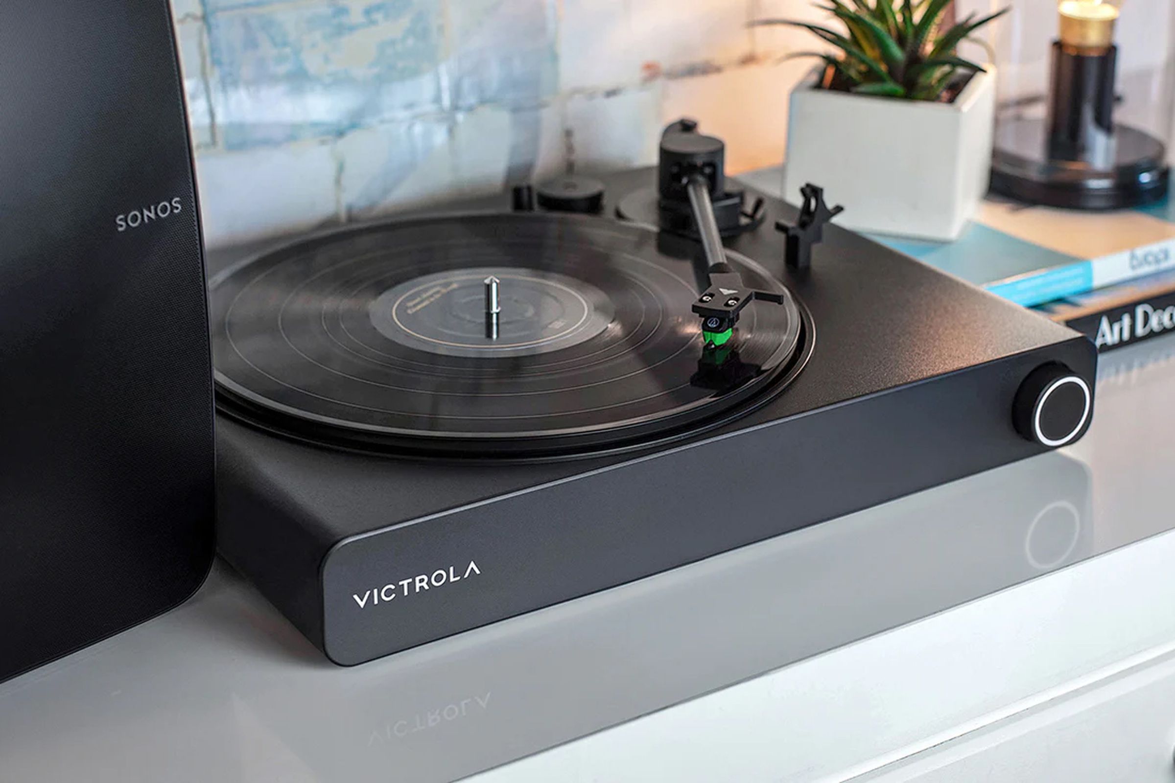 Victrola’s Stream Onyx sitting on a cabinet between a Sonos speaker and a potted plant.