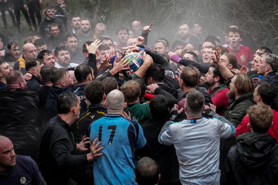 Players wade through the River Henmore as they fight for the ball during this week's match. (Christopher Furlong/Getty Images)