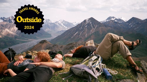 A group of hikers stretch out atop Divide Peak in Denali National Park, Alaska, with an incredible view over the peaks.