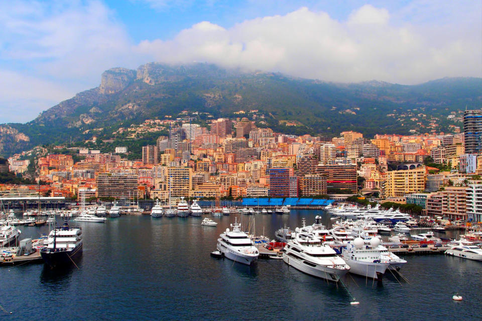 Yachts in a harbor with a hilly city in the background