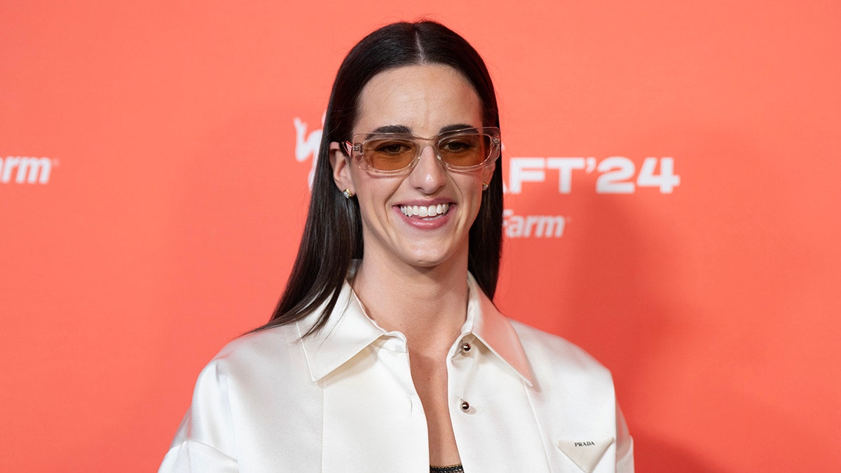 Caitlin Clark smiles on orange carpet