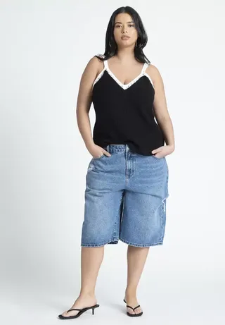 Woman wearing Eloquii baggy bermuda denim shorts