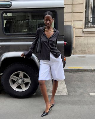 Woman wearing a black top, long white shorts, and heels