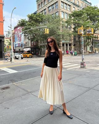 Olivia Perez wearing a black tank top and white midi skirt