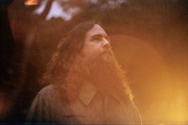 A bearded man stands in the glow of the sun.