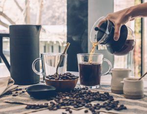 making coffee with coffee beans, a water carafe, and a cup