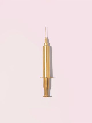 Gold injection needle on a pink background