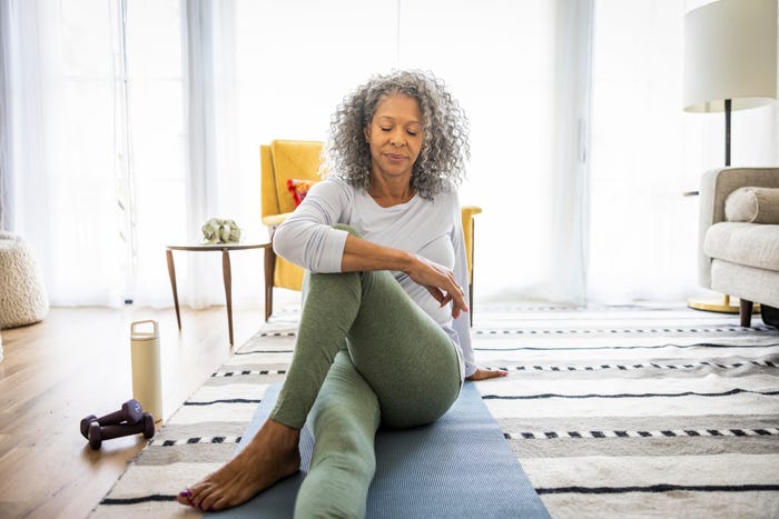 An older woman stretches on a yoga mat.