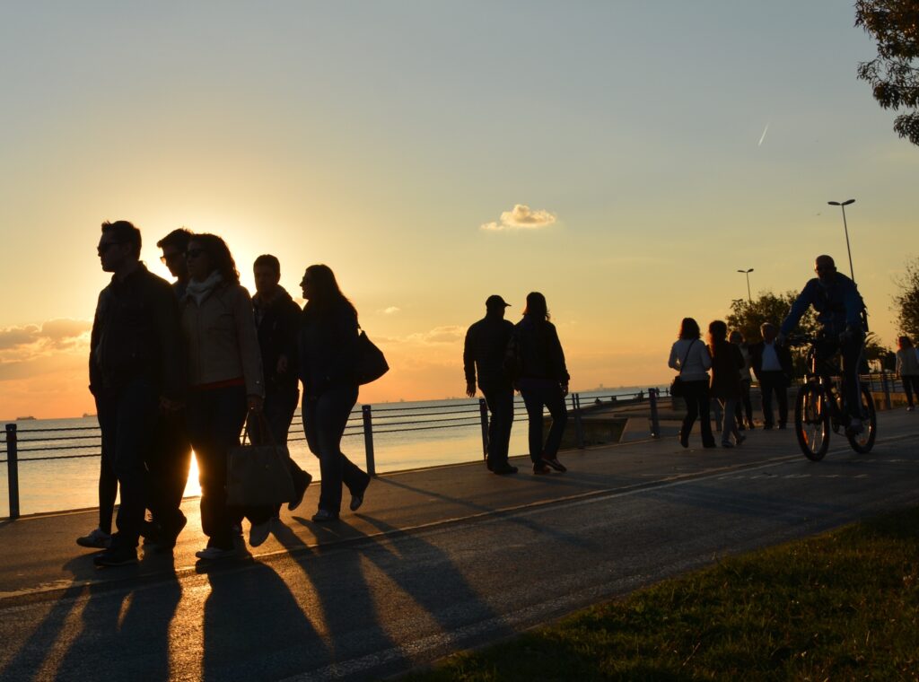 a bunch of people walking running and biking on an oceanside promenade