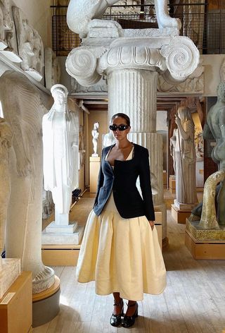 a photo of a woman's white dress outfit styled with a black blazer, black pumps and black sunglasses