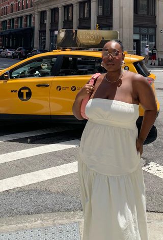 a photo of a woman's white dress outfit with strapless maxi styled with hoop earrings, a gold chain, rimless sunglasses and a pink shoulder bag