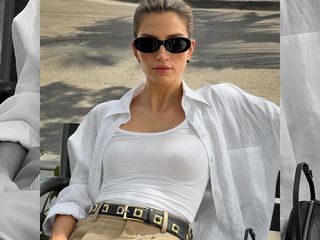 Influencer Cass Dimicco poses on a bench wearing black oval sunglasses, white linen button-down shirt, white tank top, embellished belt, and tan pants.