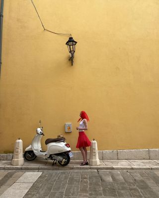 Christie Tyler wearing a red scarf, white tank top, and red J.Crew skirt.