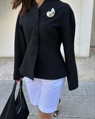 Debora Rosa wearing a black blazer, white shorts, and a silver Zara brooch.