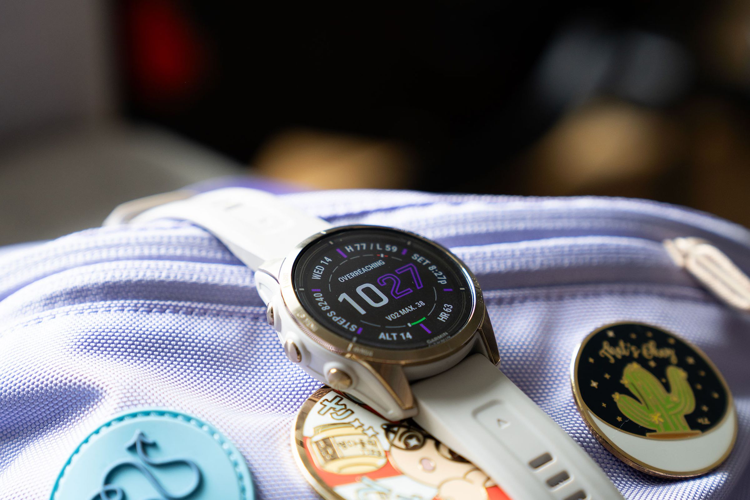 Garmin Epix Pro on top of a lavender bag with multiple enamel pins.